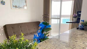 Een woonkamer met een bruine bank, een glazen deur naar een balkon en een granieten aanrechtblad.