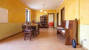 A dining area with a wooden table, chairs, and a cabinet. There is a red chair and a wooden bench with a cushion. - Lovely home in Laureana Cilento (Laureana Cilento)