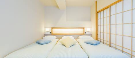 Una habitación con una cama de madera baja, un ventanal con vistas y una lámpara en el techo.