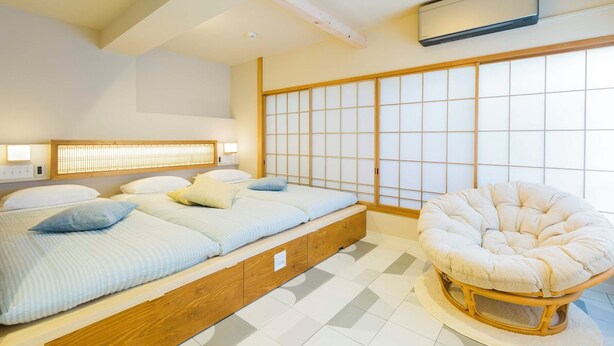 A modern bedroom with a low platform bed, a traditional Japanese shoji screen wall, and a round cushioned chair. - Kago  by Tokyo Shukuba Hotel (Tokyo)