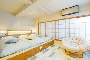 Egy modern hálószoba, melyben alacsony, platformos ágy található, valamint egy hagyományos japán shoji-féle, osztott panelekből álló fal, és egy kerek, párnázott szék.