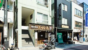 A building with a sign for 'GUST HOUSE' and another sign for 'Shinagawa Hotel'. There is a motorcycle parked in front of the building. - Kago  by Tokyo Shukuba Hotel (Tokyo)