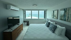 Une chambre moderne avec un grand lit, une télévision et une vue sur la plage.