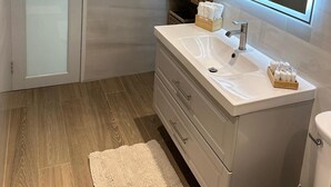 Une salle de bain moderne avec une porte en verre, un meuble-lavabo avec un miroir et un plancher en bois.