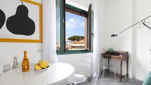 Una habitación moderna con una mesa blanca, sillas traslúcidas, una botella y vasos.