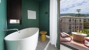 Un baño moderno con una bañera independiente, un taburete pequeño y una ventana con persiana.