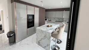 Una cocina moderna con una isla de mármol, horno empotrado y electrodomésticos de acero inoxidable.