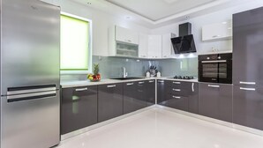 A modern kitchen with stainless steel appliances, white cabinets, and a black countertop.