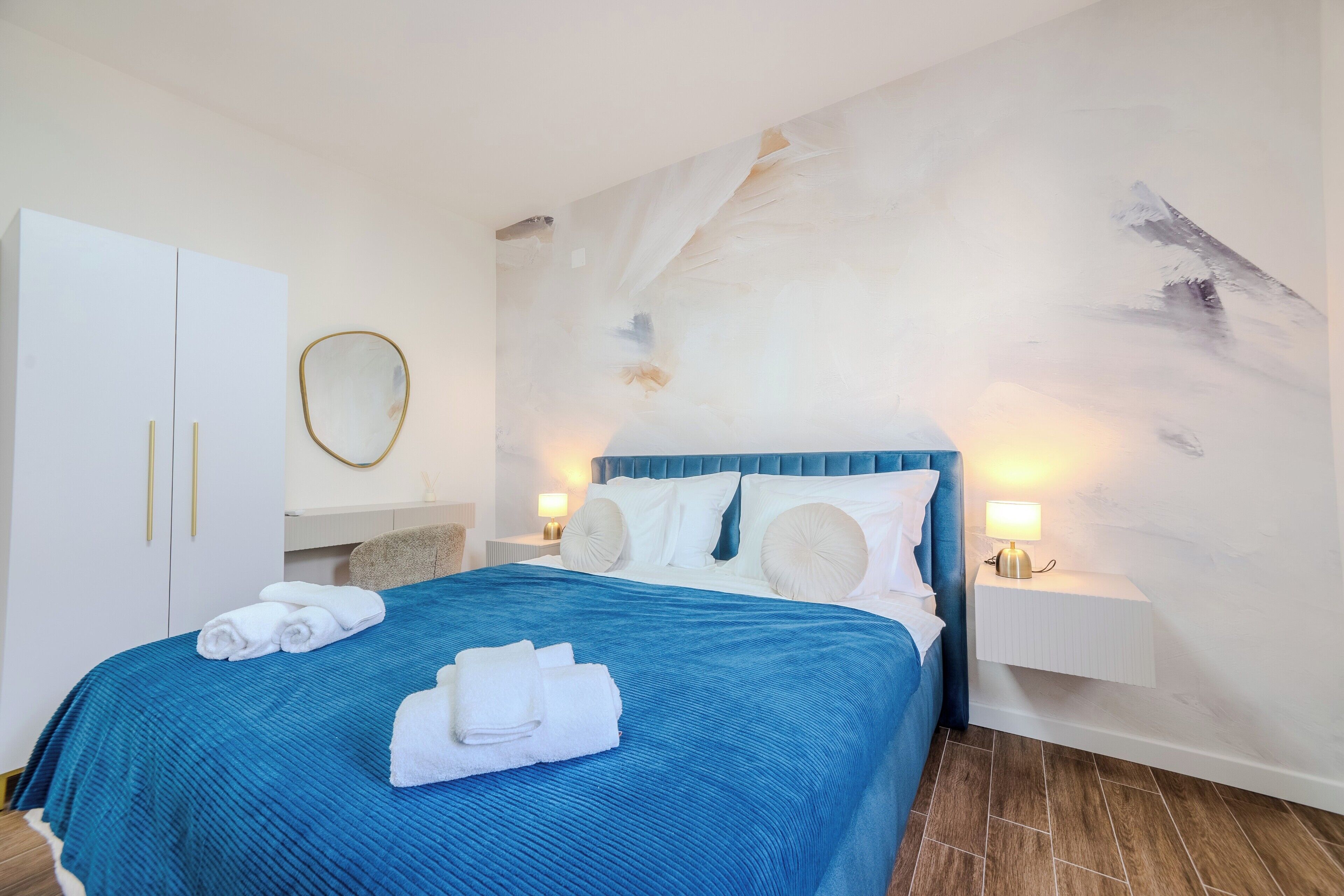Una habitación de hotel con una cama grande, un armario, un espejo y un cuadro en la pared.