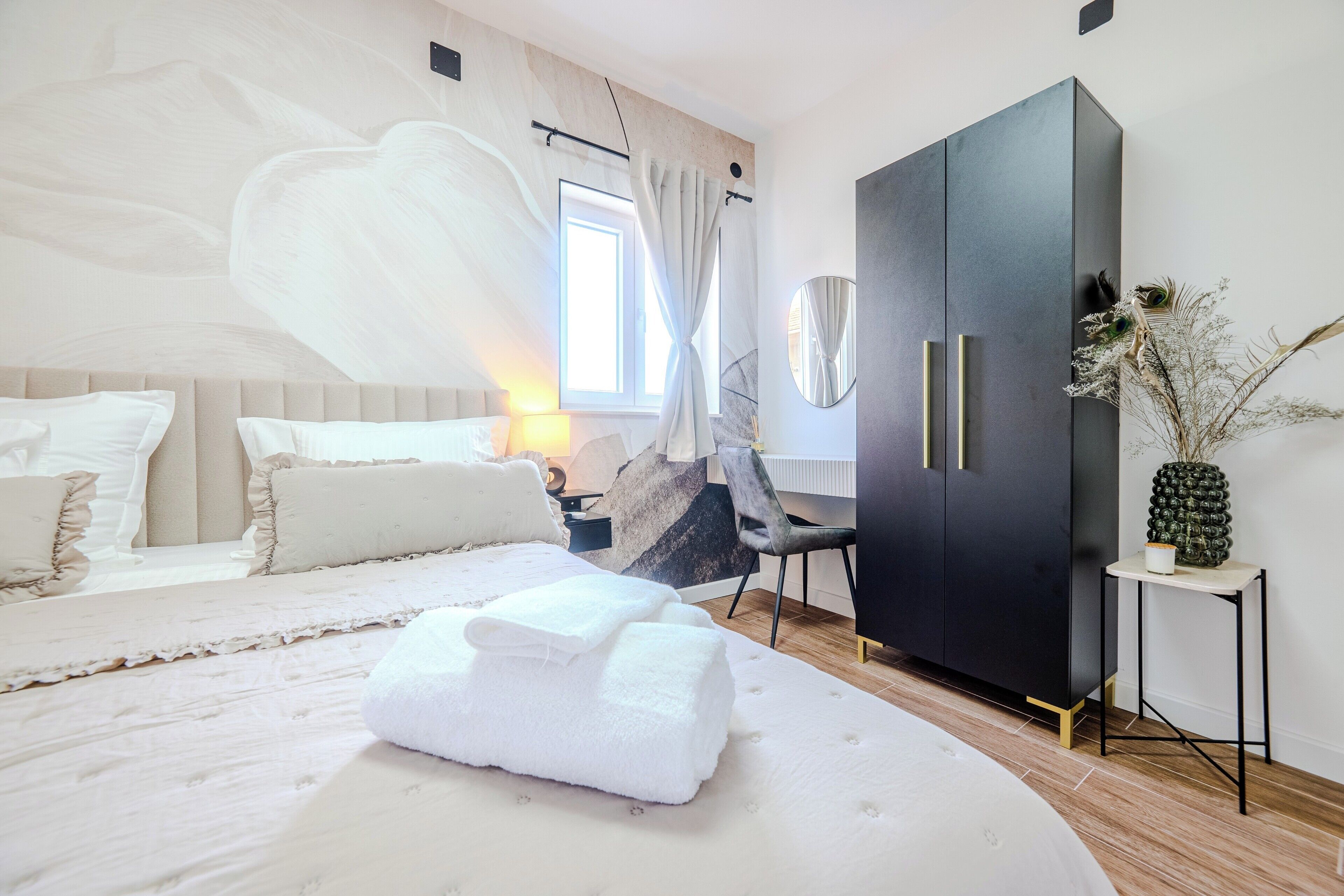 Un dormitorio moderno con una cama grande, un armario, un escritorio y un espejo decorativo.