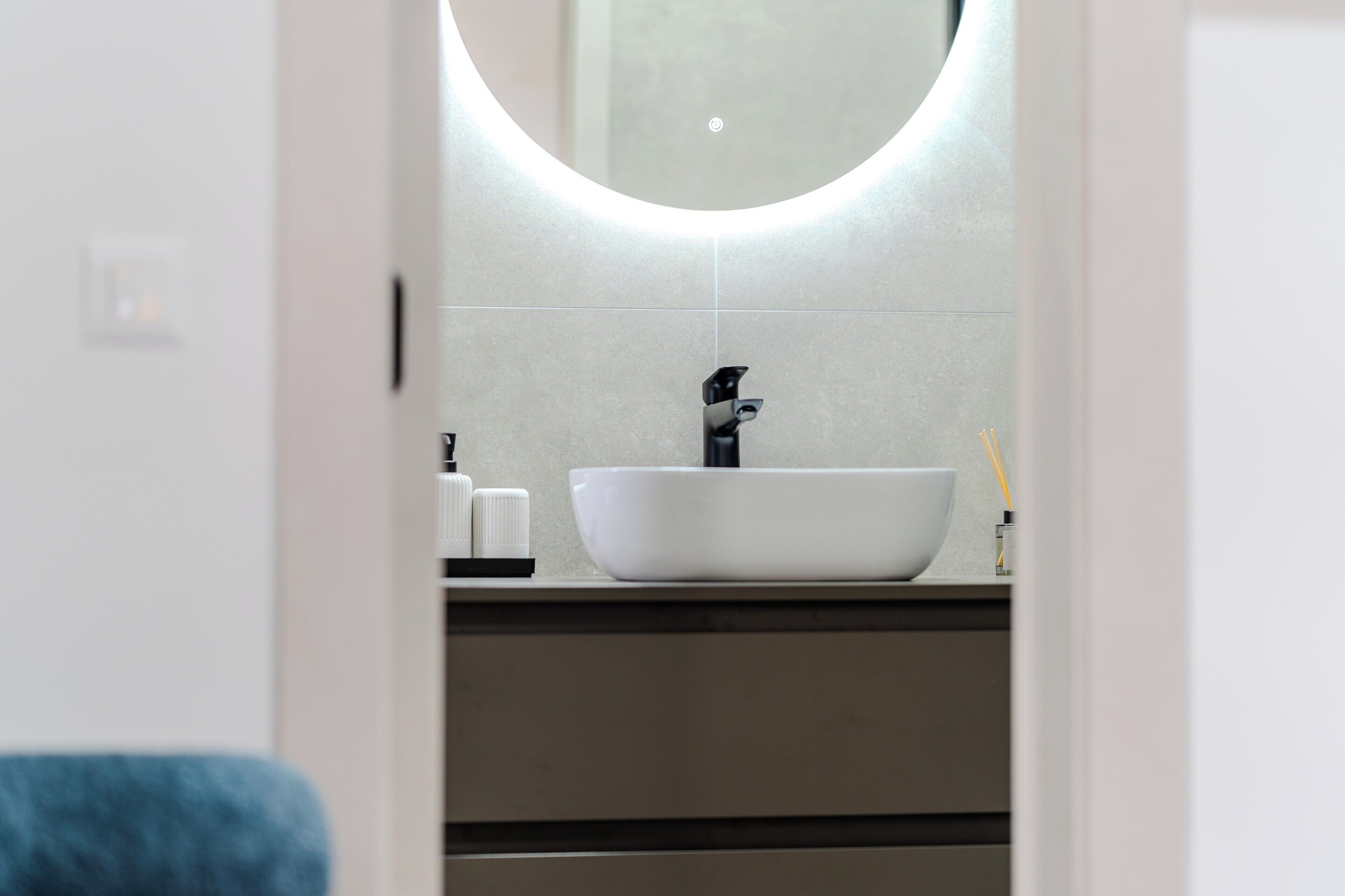 A bathroom with a white sink, a round mirror, and a towel rack.