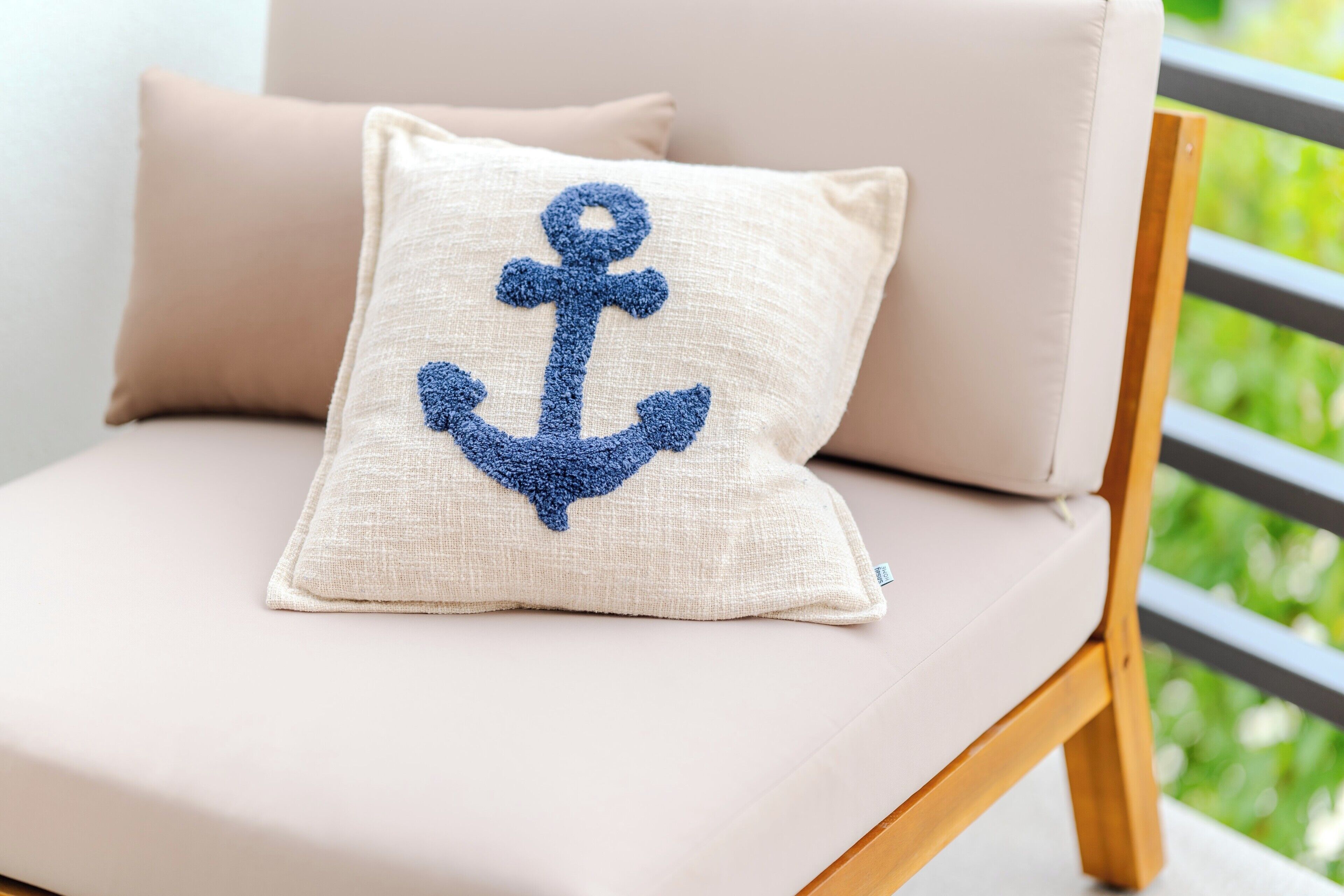 Ein Stuhl mit Kissen, verziert mit einem blauen Anker-Motiv.