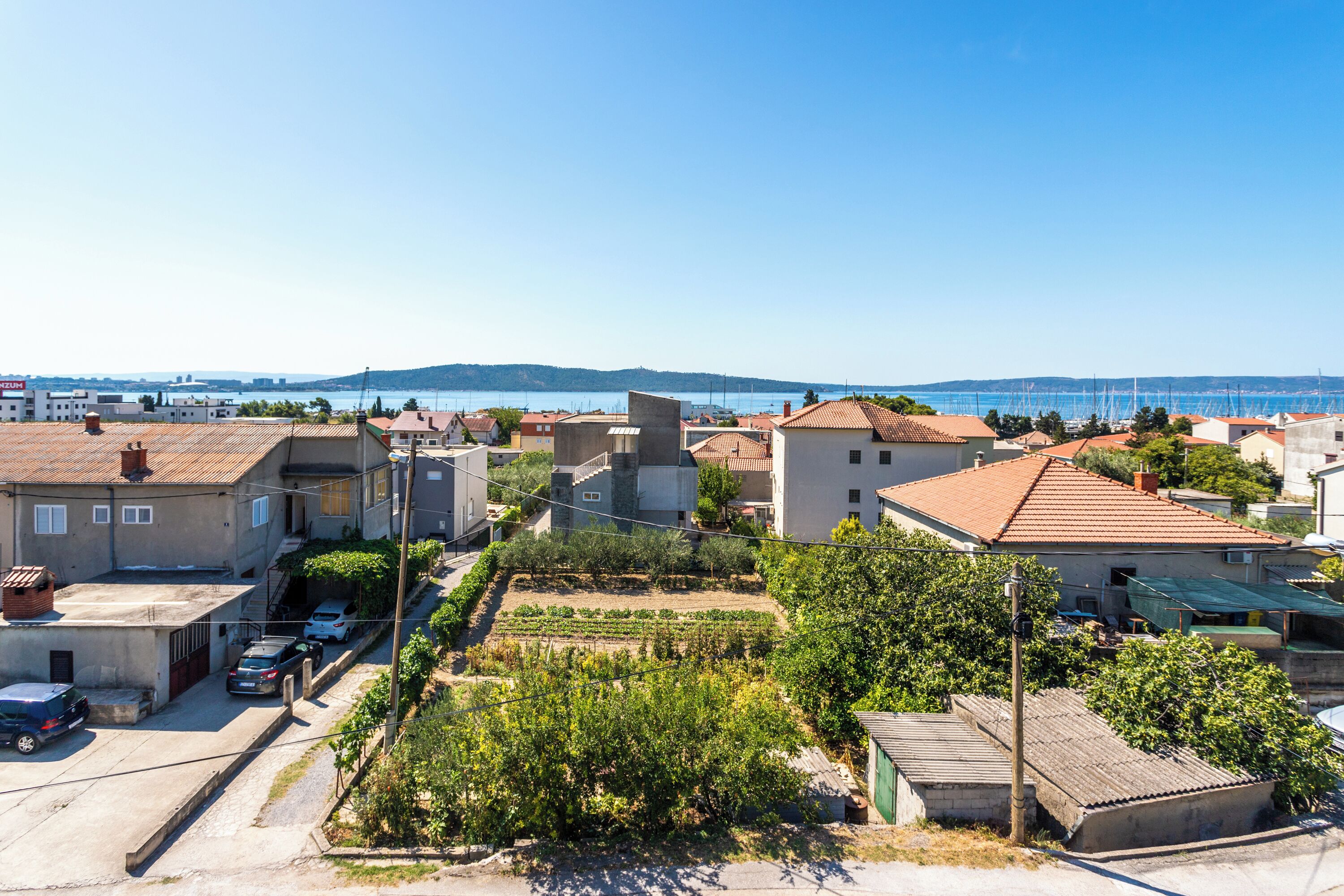 Zona residencial com casas, vinhedo e vista desimpedida do mar.