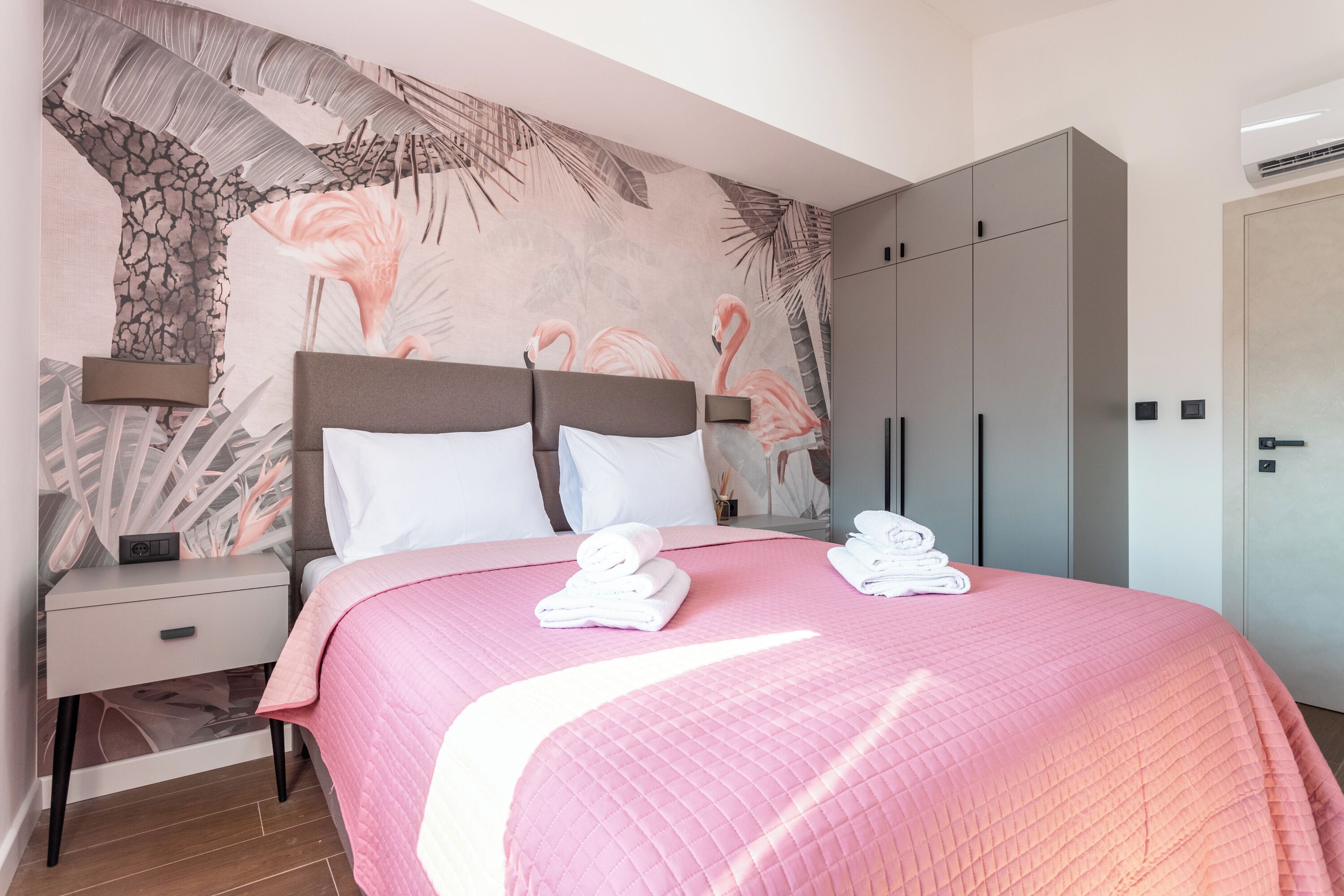 Une chambre à coucher comprenant un lit, des tables de chevet, une armoire et une fresque murale.