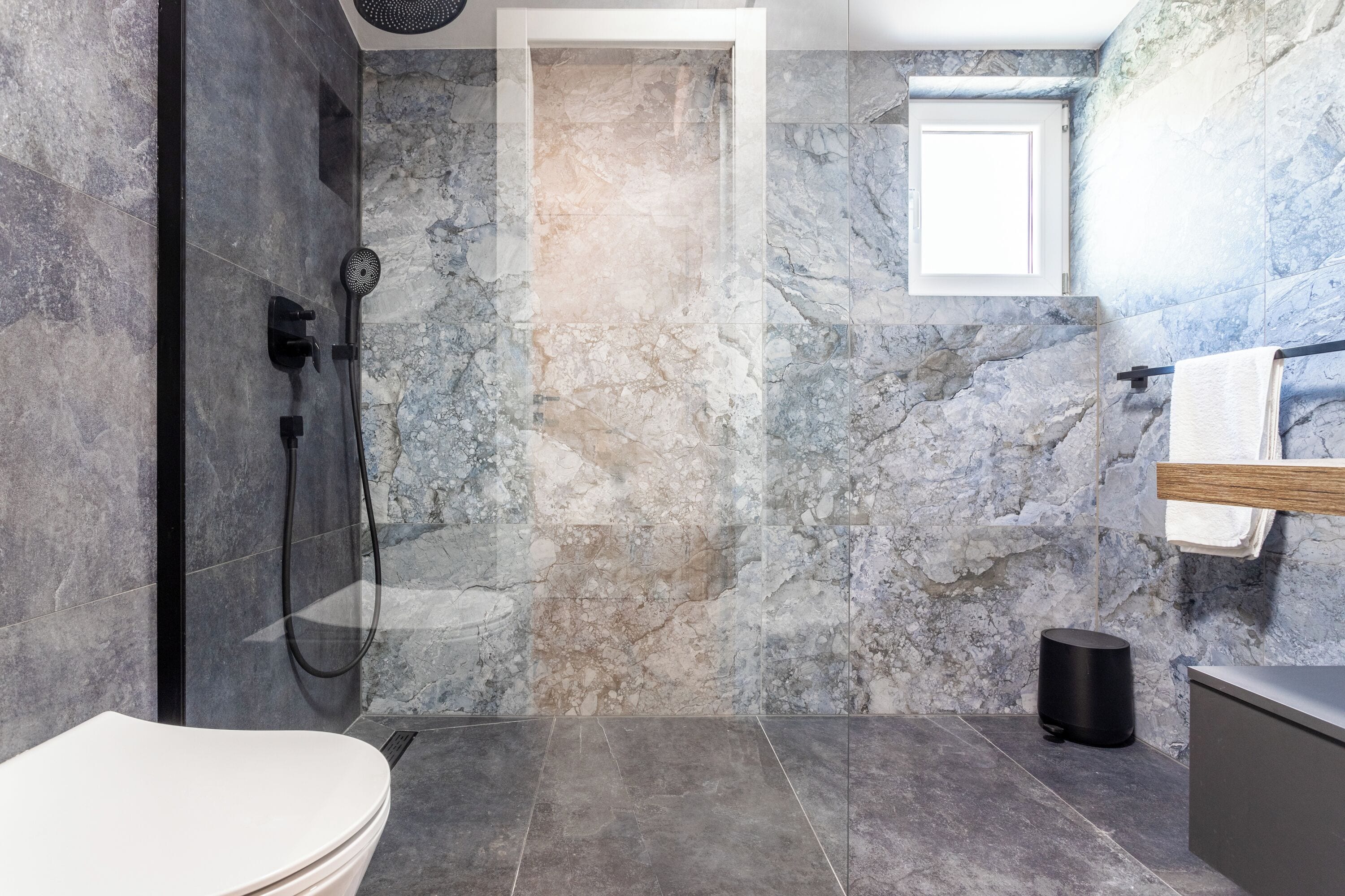A modern bathroom with a shower, toilet, and sink.