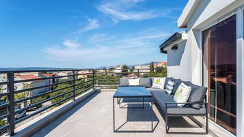 Un balcón con sofá, una mesa y barandilla con vista a una zona residencial.