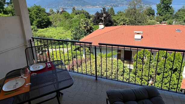 A balcony with a table set for two, overlooking a lake and mountains. - Marenco apartment in Stresa with lake view (Stresa)