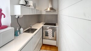 Een compacte keuken met een ingebouwde oven, een roestvrijstalen spoelbak en een klein aanrecht.