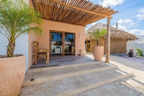 Ein Gebäude mit Strohdach, einer Holzpergola und einer Palme.