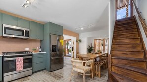 Une cuisine moderne dotée d’appareils électroménagers en acier inoxydable, d’une table à manger en bois et d’un escalier.