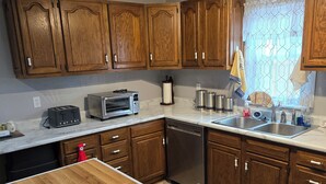 A kitchen with wooden cabinets, a countertop, a dishwasher, a toaster, and a sink. - Uniquely remodeled 3 bdrm 1 bth home in safe area! Fenced in with a large deck!  (Owensboro)