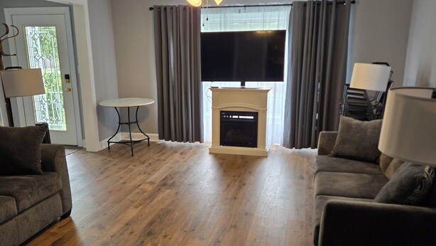 A living room with a fireplace, a ceiling fan, and a flat-screen TV. - Uniquely remodeled 3 bdrm 1 bth home in safe area! Fenced in with a large deck!  (Owensboro)