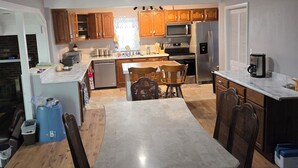 A compact kitchen with wooden cabinets, a central island, and a dining area with chairs. - Uniquely remodeled 3 bdrm 1 bth home in safe area! Fenced in with a large deck!  (Owensboro)