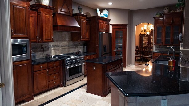 Una cocina con armarios de madera, electrodomésticos de acero inoxidable y encimera de granito negro.