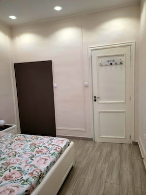 A bedroom with a bed, a wardrobe, a door, and a light switch on the wall. - Welcome to Downtown Algiers (the Main Post Office) (Alger Centre)