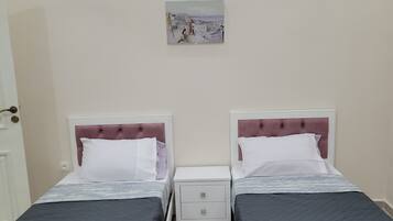 A twin room with two beds, a nightstand, a drawer, and a painting on the wall.