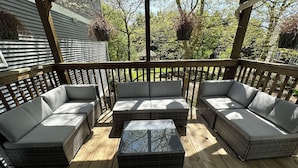 Una terraza de madera con mobiliario de mimbre, incluyendo sofás y una mesita de centro.