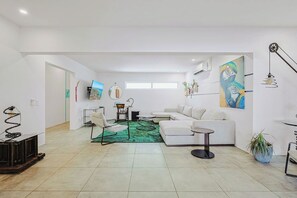 Una sala de estar moderna con alfombra verde, sofá blanco y un cuadro en la pared.