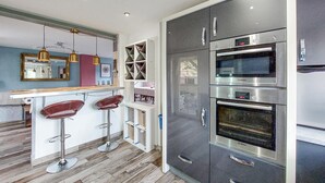 Une cuisine moderne avec un coin bar, des appareils en acier inoxydable et un plancher en bois.