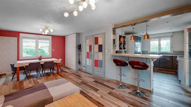 Une cuisine moderne dotée d’un grand îlot central, de murs rouges et d’un plancher en bois.