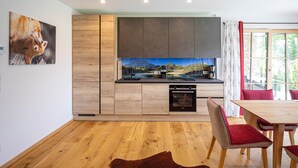 A modern kitchen with wooden cabinets, a built-in oven, and a dining area with a table and chairs. - Pet friendly apartment (Rußbach am Pass Gschütt)