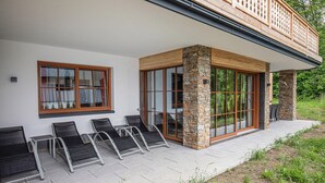 A modern building with a stone facade, large sliding glass doors, and a covered patio area with outdoor seating. - Pet friendly apartment (Rußbach am Pass Gschütt)