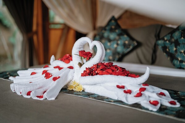 A towel arrangement with a heart-shaped design and red rose petals.