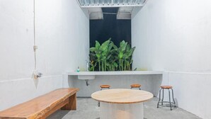A small, modern bathroom with a round wooden table, three stools, and a bench. - Santya Loka Lodge and Twin Waterfall (Tabanan)
