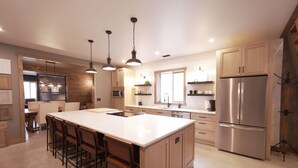 Una cocina moderna con una isla central, electrodomésticos de acero inoxidable e iluminación colgante.