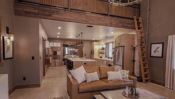 Un amplio salón con techos altos, un entrepiso de madera, una cocina y un comedor.