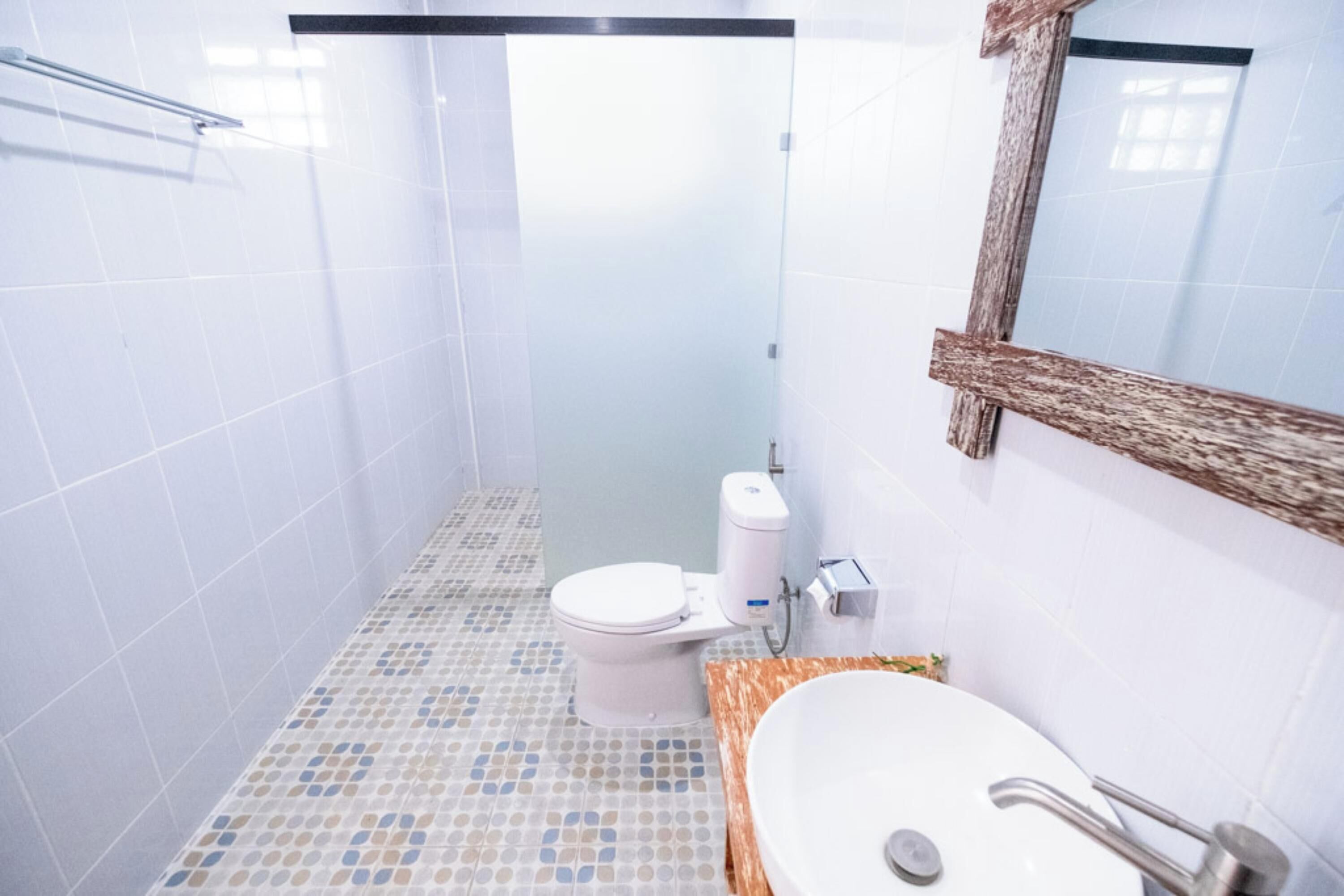 A bathroom with a tiled floor, a toilet, a sink, and a mirror.