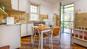Une cuisine de taille réduite comprenant un coin repas, une fenêtre et une porte donnant sur l’extérieur.