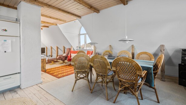 A dining area with wicker chairs and a table, a white refrigerator, and a wooden ceiling. - Beautiful apartment in Ribe with WiFi (Ribe)