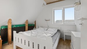 A small, bright room with a sloped ceiling, a single bed, a small bedside table, a window, and a white wardrobe. - Beautiful apartment in Ribe with WiFi (Ribe)