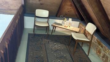 A small attic room with two chairs, a table, and a rug.
