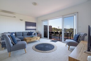 Relax in this stylish living room with a sofa, coffee table, and TV, leading to a patio area.