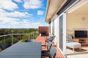 Enjoy al fresco dining and relaxation in this outdoor living space with a dining table, comfortable seating, and a flat-screen TV.
