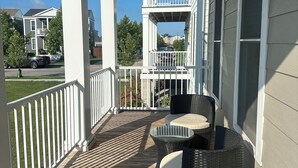 A covered porch with wicker furniture and a view of neighboring houses. - Cozy Front Lake Home in Newtown St. Charles (Saint Charles)