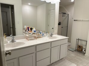 Uma casa de banho moderna com duas pias, um espelho grande e cabine de duche.