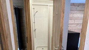 Een smalle gang die leidt naar een badkamer met een douche en een bad.
